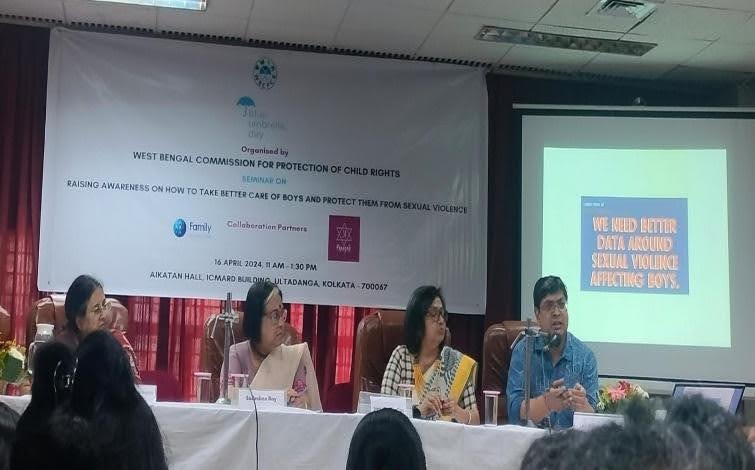 A meeting of the West Bengal Commission for Protection of Child RIghts. There are three women and a man sitting on a table as panelists in front of a class. At the bottom right, there is a powerpoint slide saying "we need better data around sexual violence affecting boys".