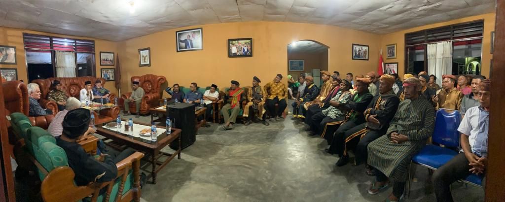 A room with people seating on chairs organised in a semi-circle.
